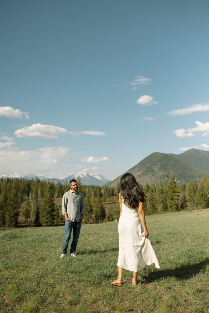 Couple embracing with mountains and fresh greenery in the background at Glacier National Park