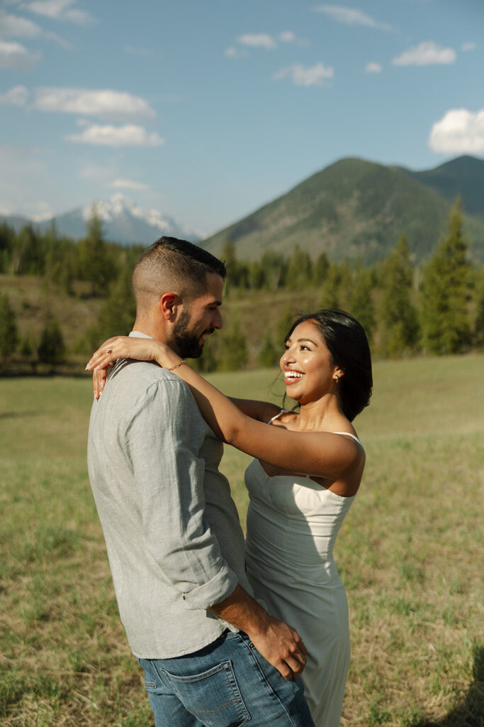 Couple holding hands in a wide open landscape during their Glacier National Park engagement session
