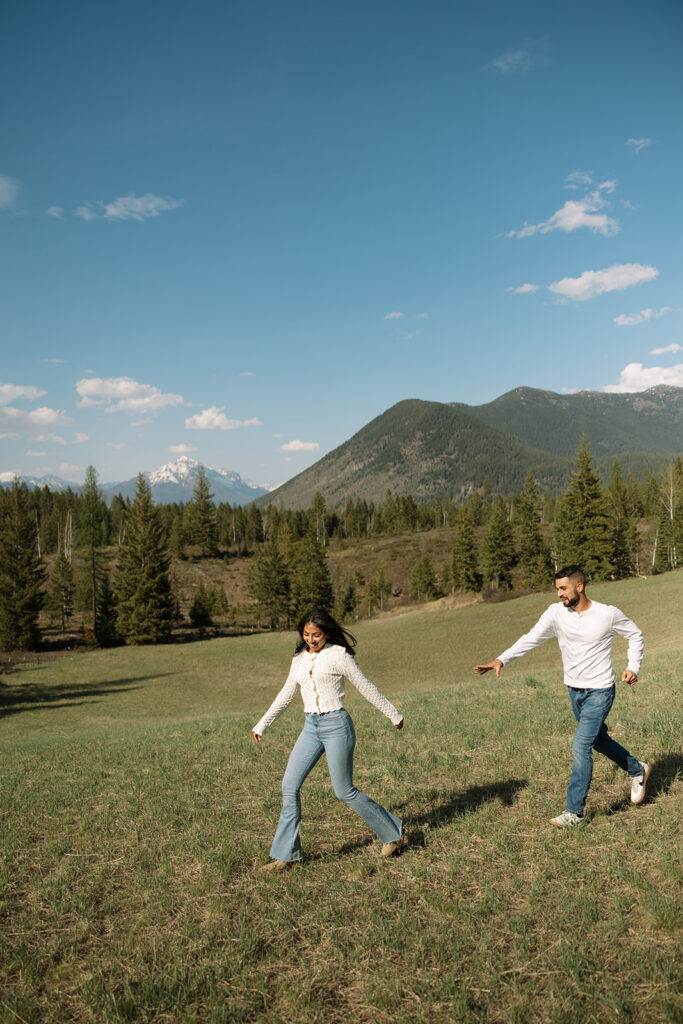 Couple holding hands in a wide open landscape during their Glacier National Park engagement session
