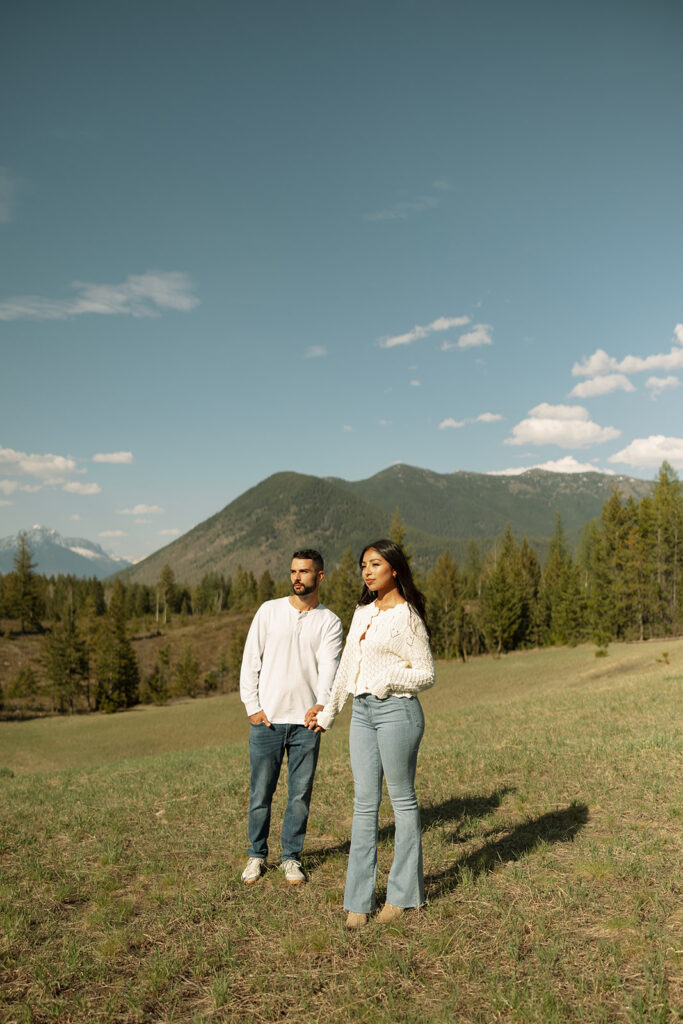 Couple embracing with mountains and fresh greenery in the background at Glacier National Park