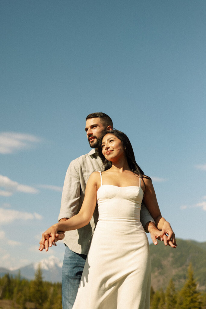Couple embracing with mountains and fresh greenery in the background at Glacier National Park