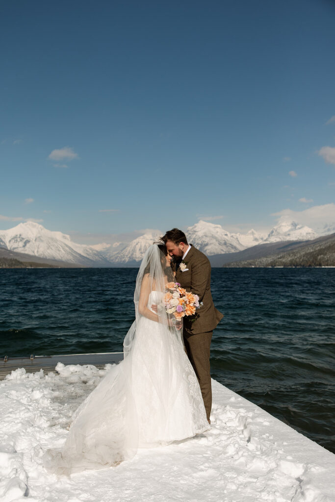 Couple walking along a frozen lake in Glacier National Park during a romantic winter elopement
