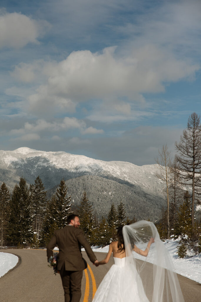 Couple walking along a frozen lake in Glacier National Park during a romantic winter elopement
