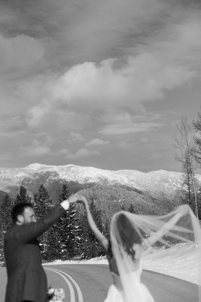 Couple walking along a frozen lake in Glacier National Park during a romantic winter elopement
