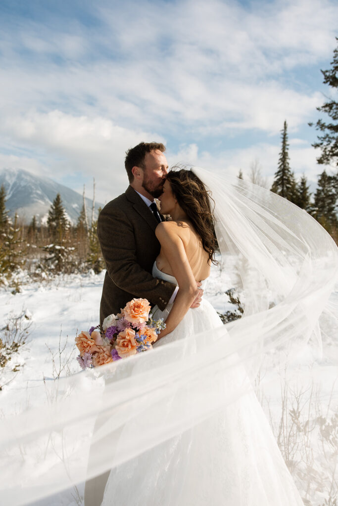 Bride and groom embracing in a snowy mountain setting during a quiet winter wedding day
