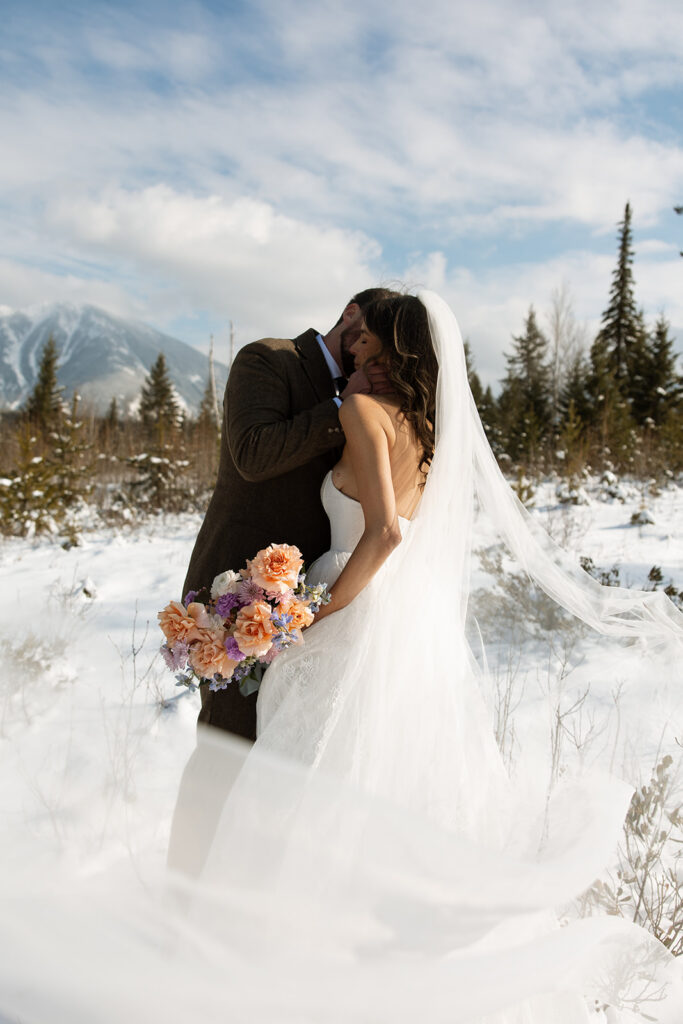 Bride and groom embracing in a snowy mountain setting during a quiet winter wedding day
