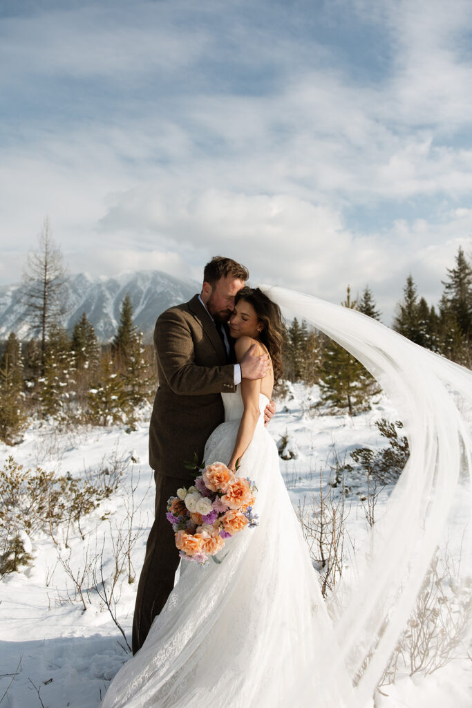 Bride and groom embracing in a snowy mountain setting during a quiet winter wedding day
