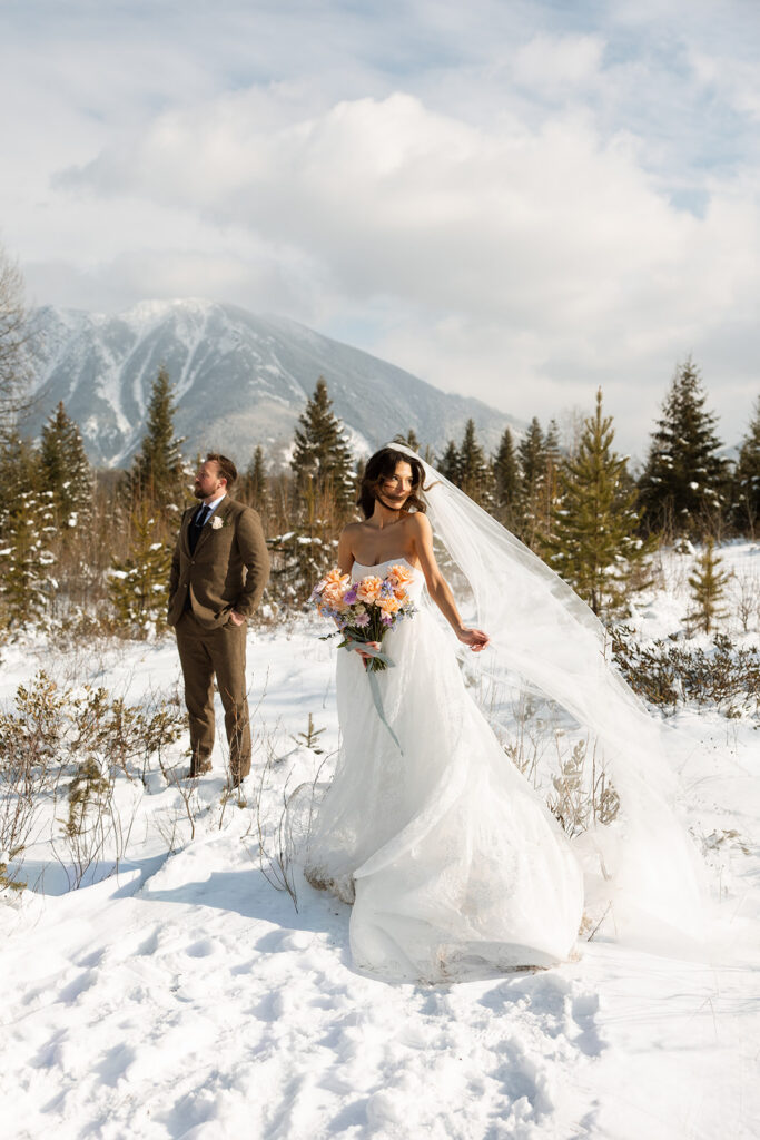 Bride and groom embracing in a snowy mountain setting during a quiet winter wedding day
