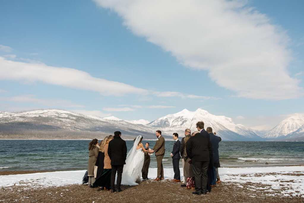Emotional ceremony during an elopement at Lake McDonald with guests gathered in a quiet snowy landscape
