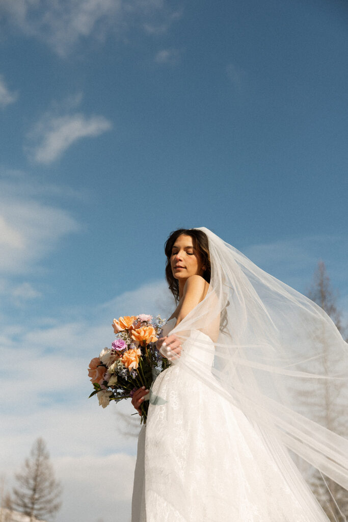 Bride and groom embracing in a snowy mountain setting during a quiet winter wedding day
