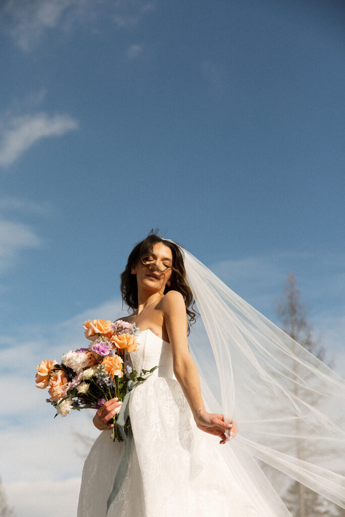 A winter elopement at Lake McDonald with a couple standing by a snowy lakeshore surrounded by mountains