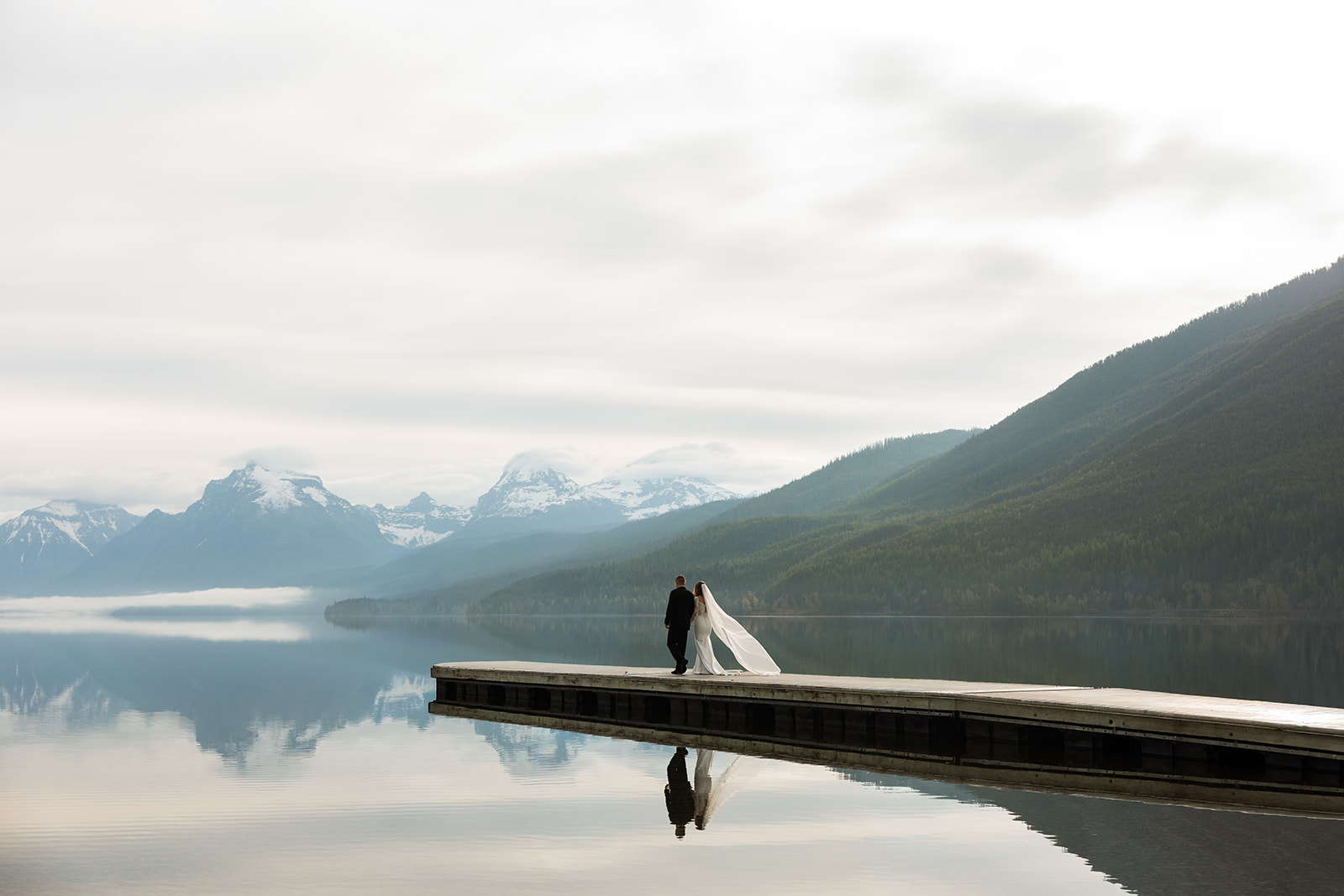 Couple embracing during a sunset elopement in Glacier National Park with mountain views in the background