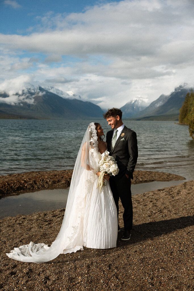 Bride and groom sharing intimate moments along the shoreline of Lake McDonald in Glacier National Park.