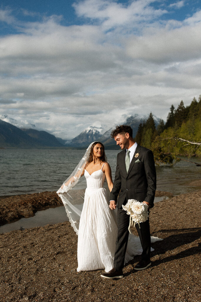Bride and groom sharing intimate moments along the shoreline of Lake McDonald in Glacier National Park.